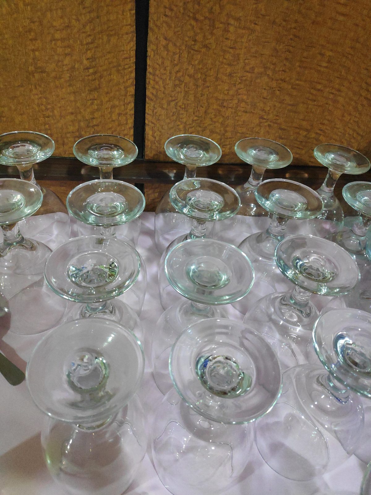 About twenty wine and champagne glasses standing upside down on a pale surface