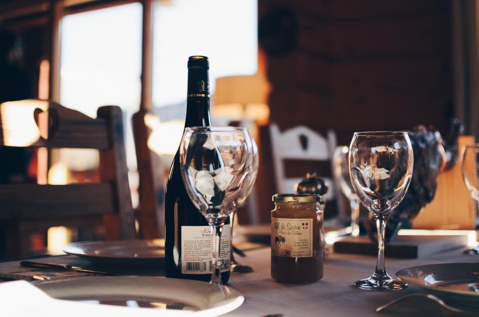 A laid table in a sunlit dining room with a wine bottle and glasses