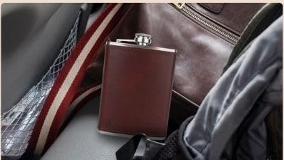 8 oz leather wrapped hip flask held in one hand to show scale